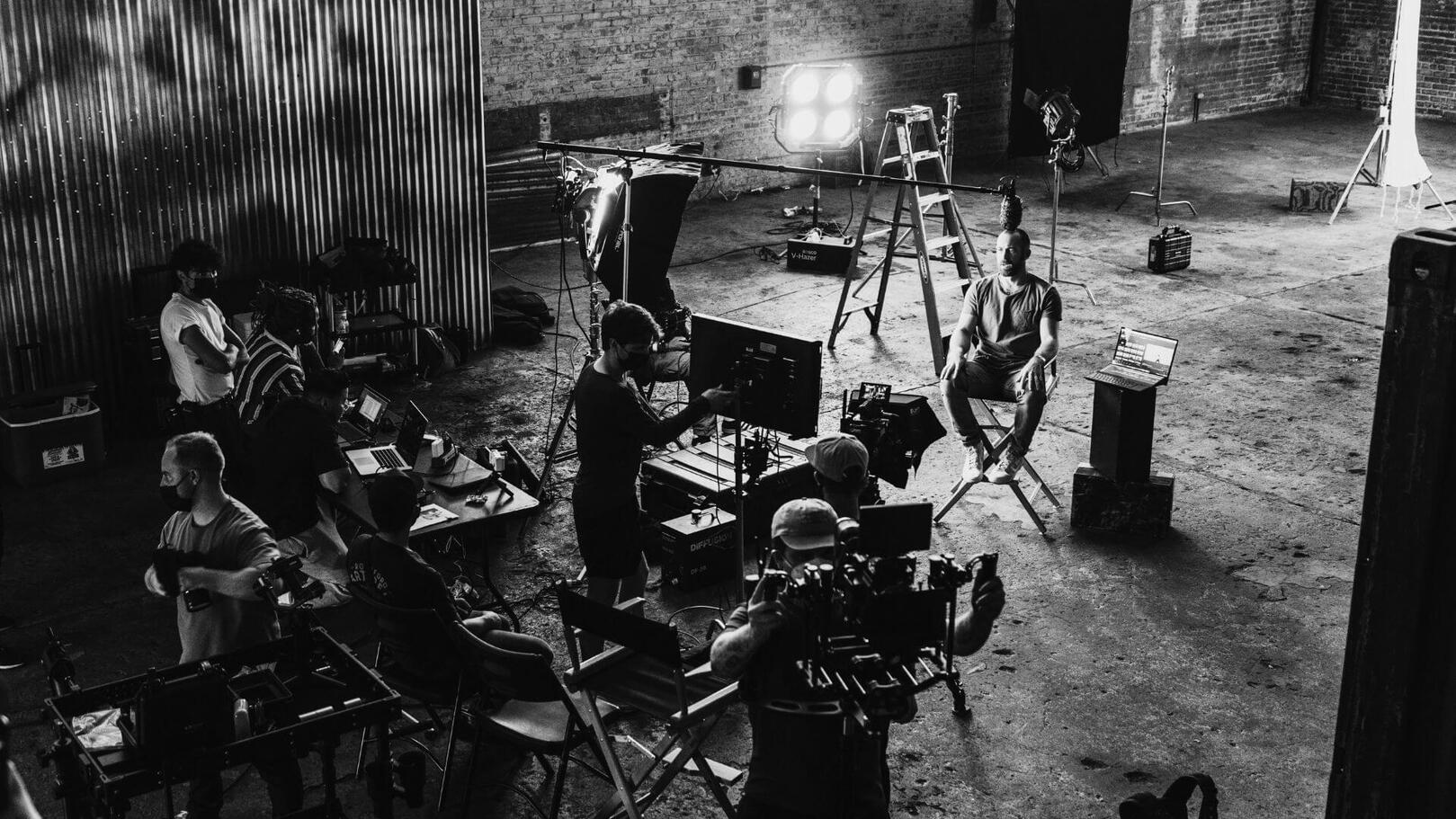 Set Coordination & Logistics — Workflows and Setup | Jessica Evelyn Rodrigues de Lima Top-down aerial view of a film set during setup, featuring studio lights, a director’s chair, monitors, and the crew actively working on location.
