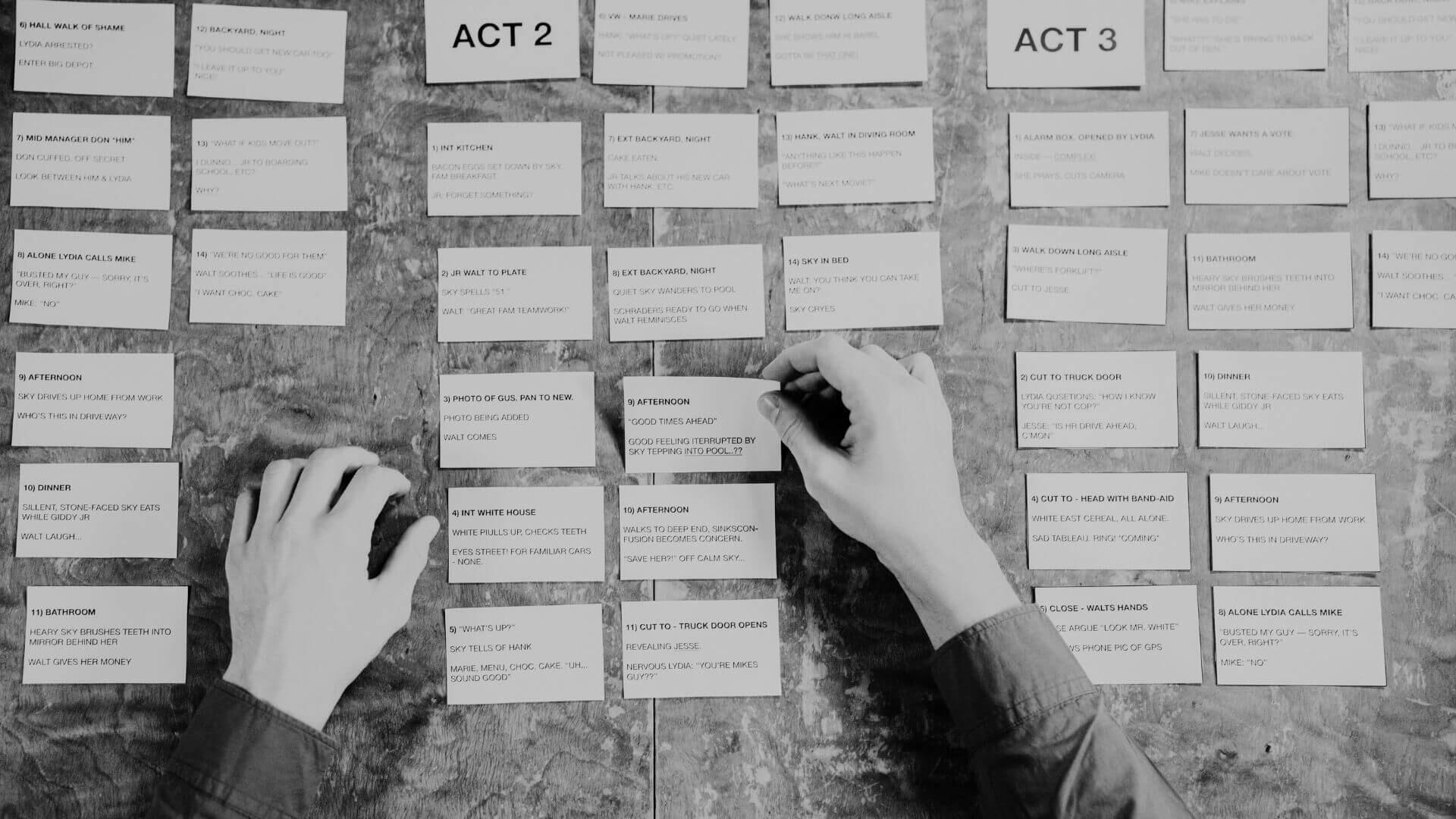 Script Review & Narrative Architecture — Jessica Evelyn Rodrigues de Lima Hands organizing and reviewing narrative planning index cards divided into three acts on a workspace desk.