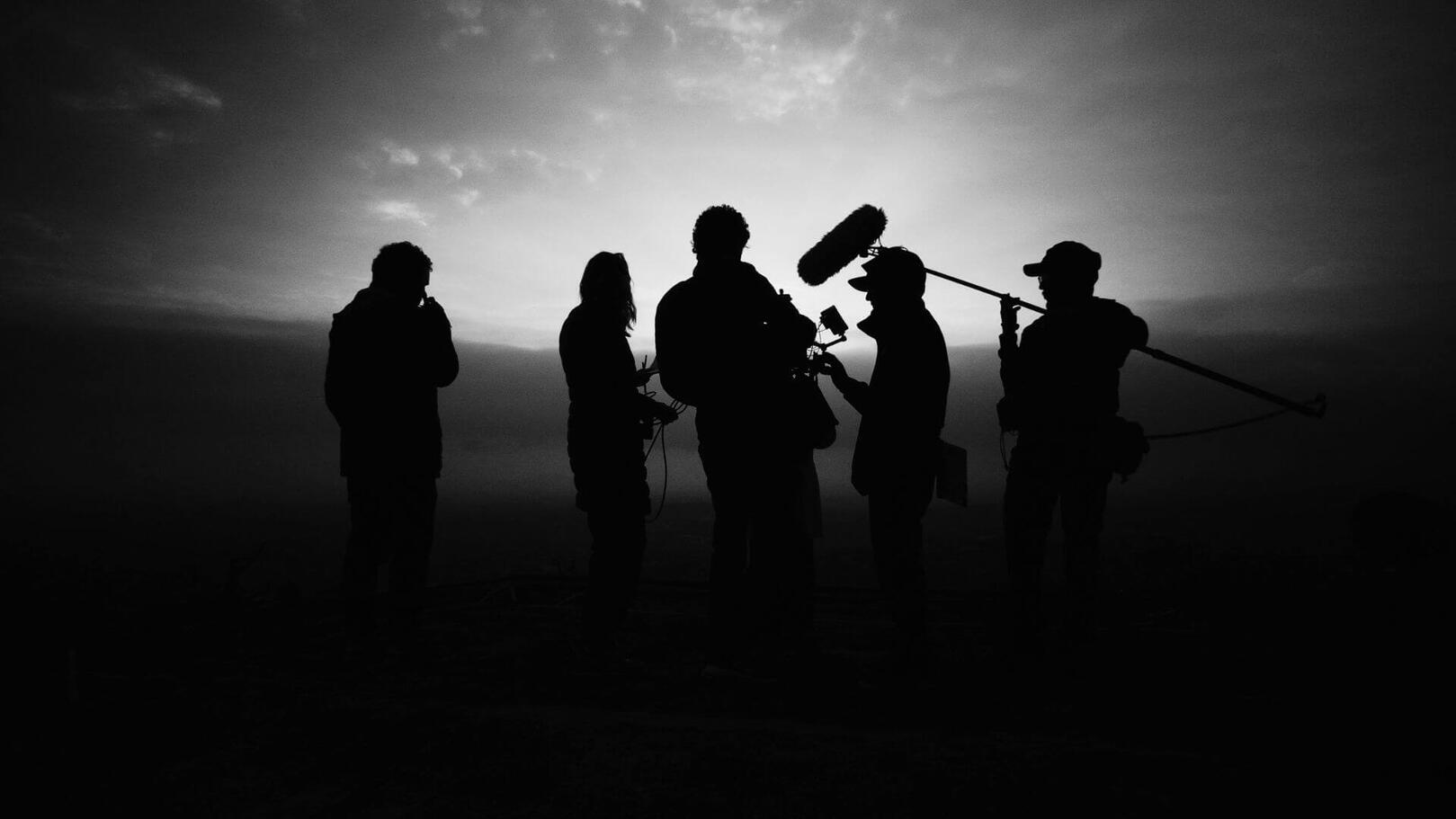 Team Leadership & Crew Direction — Audiovisual Coordination | Jessica Evelyn Rodrigues de Lima Film crew members focused around a production monitor reviewing footage under cinematic studio lights.